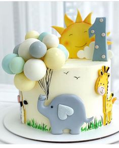 a birthday cake with an elephant, giraffe and balloon topper on it