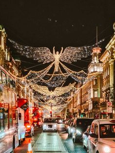 cars are driving down the street with christmas lights strung across it and angel decorations above them