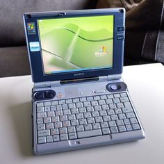 an open laptop computer sitting on top of a white table next to a gray couch