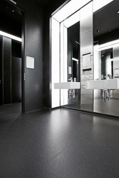 an empty bathroom with mirrors and sinks in it's black color scheme is shown