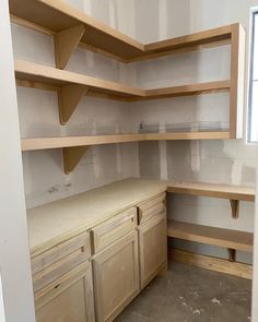 a room with some shelves and cupboards in the corner next to a window that has no curtains on it