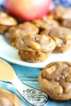 two white plates topped with apple cinnamon muffins next to an apple and spoon