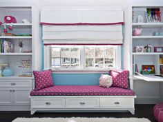 a white and blue room with a pink polka dot pillow on the futon bed