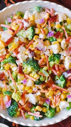 a white bowl filled with corn, broccoli and carrots on top of a table