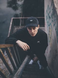 a young man leaning against a wall with his hand on the railing