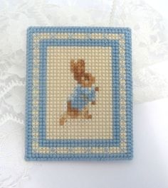 a cross stitch picture with a teddy bear on it's back and blue trim