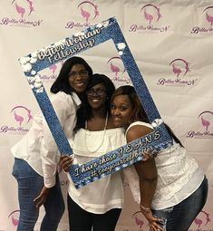 three women pose for a photo in front of a backdrop with the words happy birthday written on it