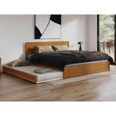 a bed sitting on top of a hard wood floor next to a wall mounted painting