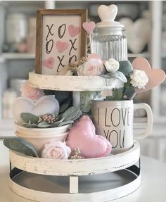 three tiered cake with flowers and hearts on the top, next to a sign that says i love you