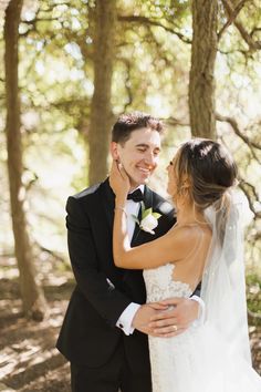 a bride and groom standing together in the woods