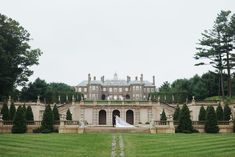 a bride and groom standing in front of a large mansion