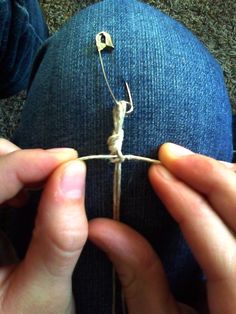 someone is tying the end of a pair of jeans with a string and two small hooks