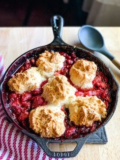 a cast iron skillet filled with crumbled food on top of a wooden table