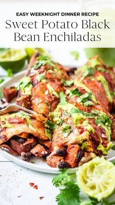 a white plate topped with black bean enchiladas next to cilantro