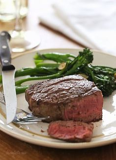 a steak and asparagus on a plate with a knife