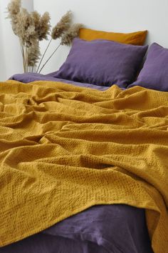 a bed with purple sheets and yellow blankets