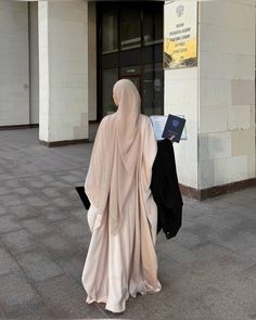 a woman walking down the street with a book in her hand and a veil over her head