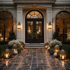 the front entrance to a house with lit candles and flowers on the ground next to it