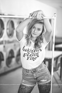 a woman is posing for a photo in front of washing machines with her hands on her head