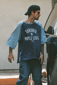 a man in a toronto maple leafs t - shirt stepping out of a car