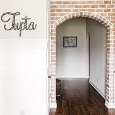 the entry way to a house with a brick archway and wooden flooring that reads tufta