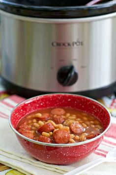 a red bowl filled with beans and sausage next to an instant pot on a table