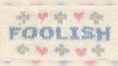 a knitted sign that says woolley on it's side with hearts and arrows