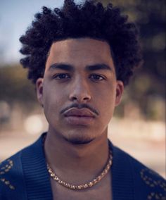 a close up of a person wearing a necklace and a jacket with an afro haircut