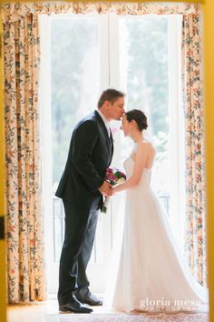 a bride and groom standing in front of a window