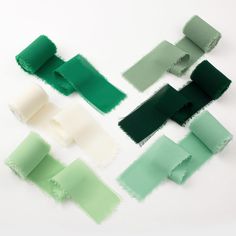 four different shades of green, white and black paper on a white surface with torn edges