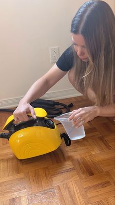 a woman kneeling down on the floor with a yellow and black blow dryer next to her