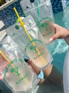 two people holding drinks in front of a swimming pool with straws sticking out of them