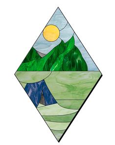 a stained glass window with mountains and trees in the background, on a white surface