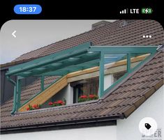 an open window on the side of a house with green roofing and flower boxes