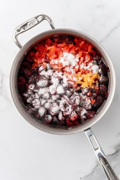 a pot filled with food sitting on top of a white marble counter next to utensils