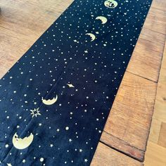 a black table runner with stars and moon designs on it, sitting on a wooden floor