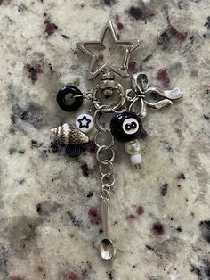 a keychain with charms attached to it sitting on a marble counter top next to a bottle opener