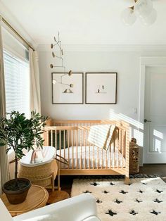 a baby's room with a crib, chair, and potted plant