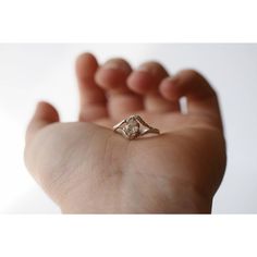 a person's hand holding a ring with a diamond in the middle on it