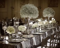 the tables are set with silver and white flowers