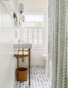 a bathroom with a checkered tile floor and white walls, along with a gold faucet