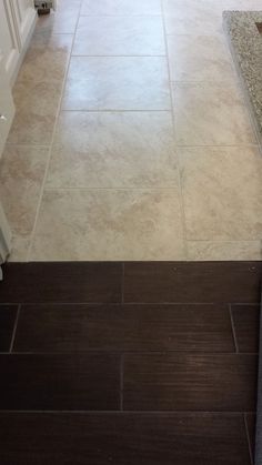 a kitchen with white cabinets and wood flooring next to a counter top on a tile floor