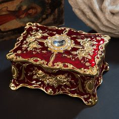 a red and gold jewelry box sitting on top of a table