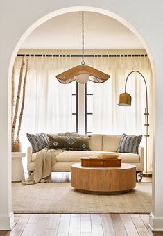 a living room filled with furniture next to a white curtained window covered in curtains