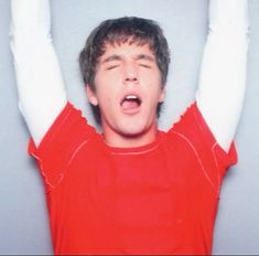 a young man with his hands in the air while wearing red shirt and white gloves