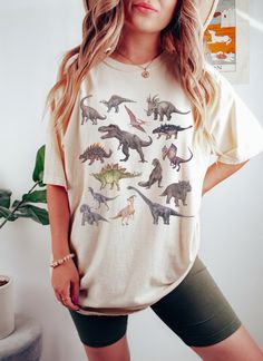 This fun dinosaur print shirt features realistic drawings of all your favorite dinos. This will become your new favorite shirt that you reach for again and again. * Q U I C K * F A C T S * ♥ 100% cotton medium weight shirt ♥ Design is high quality digital print ♥ Wash and dry normally (on cool for best results) * S I Z I N G * ♥ Sizing is unisex so runs like men's ♥ Relaxed fit shirt ♥ Please see size guide in listing photos for all measurements and information * S H I P P I N G * T I M E S * ♥ Dinosaur Shirt Aesthetic, Womens Dinosaur Shirt, Dinosaur Party Outfit Women, Mom Dinosaur Shirt, Dinosaur Shirt Women, Dinosaur Outfit Women, Dinosaur Clothes Women, Dinosaur Outfit Aesthetic, Dinosaur T Shirt