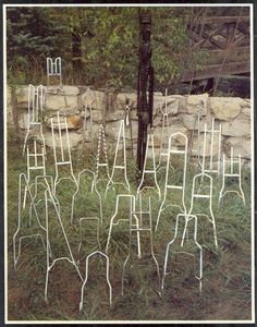 there are many white chairs in the grass near a rock wall and tree stumps