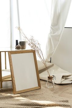 an empty wooden frame sitting on the floor next to a table with a plant in it