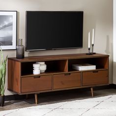 a flat screen tv sitting on top of a wooden entertainment center next to a potted plant