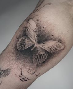 a black and white photo of a butterfly tattoo on the left arm, with two butterflies flying around it